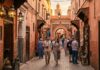 How to Avoid Scams in Marrakech: A Complete Safety & Fraud Prevention Guide Tourists walking safely through Marrakech medina terracotta alley at golden hour