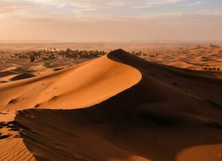 Merzouga Travel Guide: Gateway to Morocco’s Erg Chebbi Dunes Sweeping sunrise over towering orange sand dunes of Merzouga Erg Chebbi