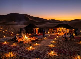 Morocco Sahara Desert Guide: Erg Chebbi vs Erg Chigaga, Camps & Logistics Traditional Berber luxury desert camp with lanterns in Erg Chebbi sand dunes at dusk