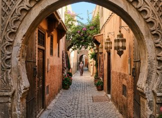 Morocco Travel Tips for First-Time Visitors: 25 Essential Things to Know Quiet sunlit cobblestone alleyway through stone keyhole archway in Moroccan medina