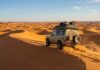 How to Visit the Sahara Desert: Tour vs Self-Drive & Planning Steps 4x4 expedition vehicle navigating the golden orange dunes of the Sahara Desert