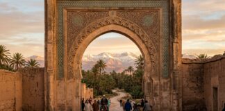 Travel to Morocco: Gateway arch framing palm trees and snow-capped Atlas Mountains