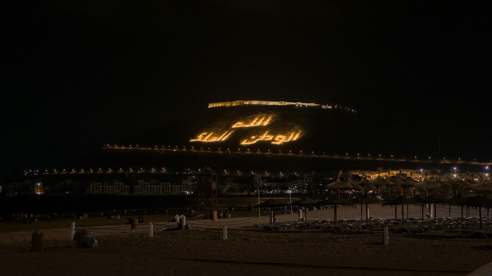 Agadir Morocco Africa: the illuminated Arabic inscription on the hill above the beach at night
