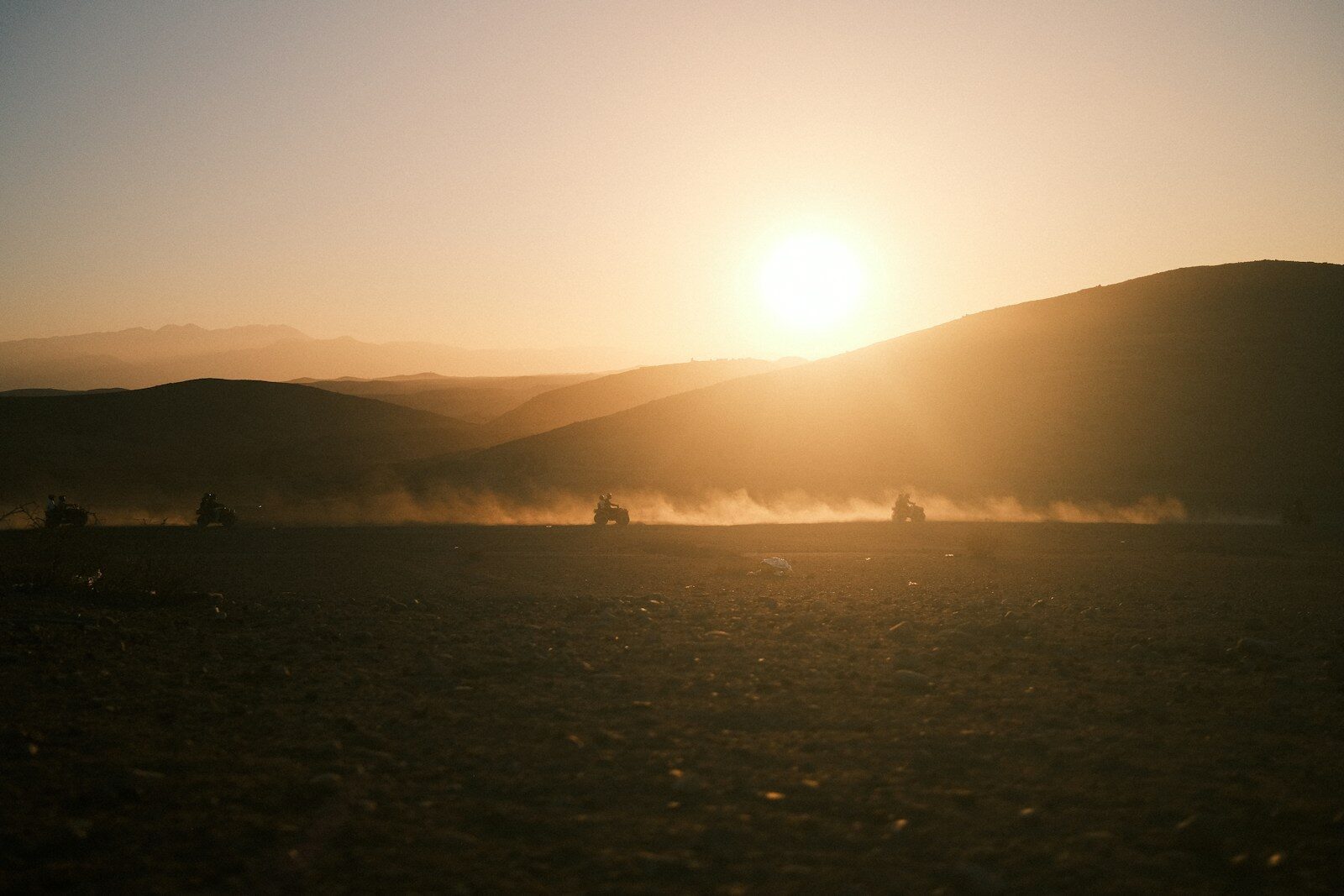 Quad bikes kicking up dust at sunset in Agafay Morocco