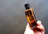 Argan Oil Guide: 12 Uses for Hair and Skin, Real Benefits and How to Buy It Pure Argan oil in an amber glass dropper bottle held in hand