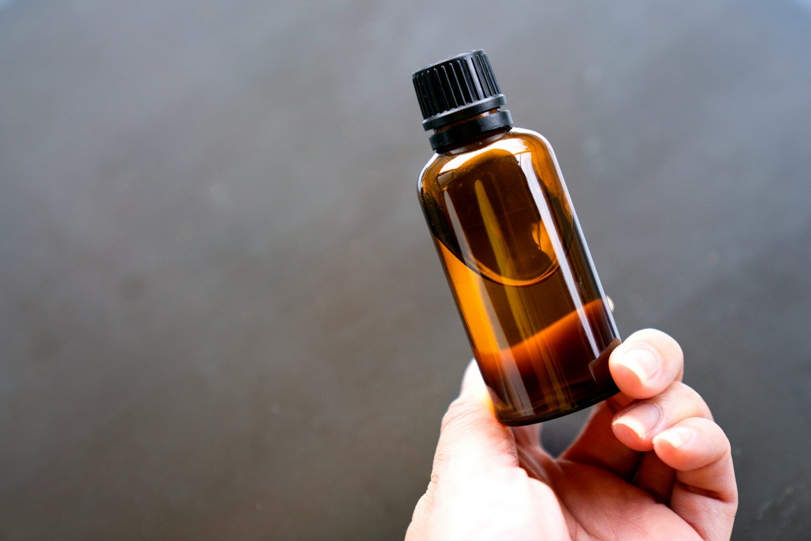 Argan oil in an amber glass dropper bottle held in hand