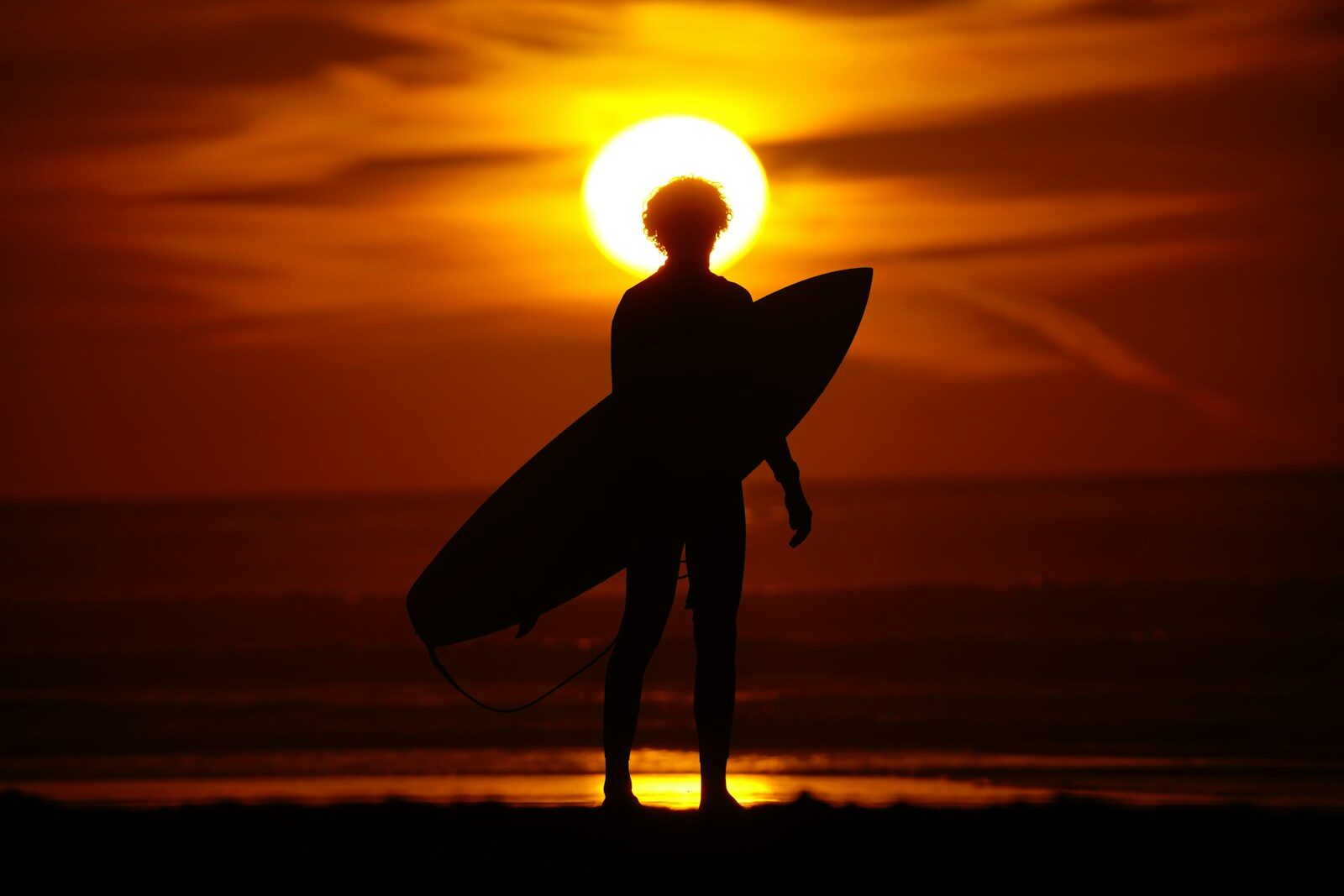 Best places to visit in Agadir Morocco: a surfer carrying a board at sunset
