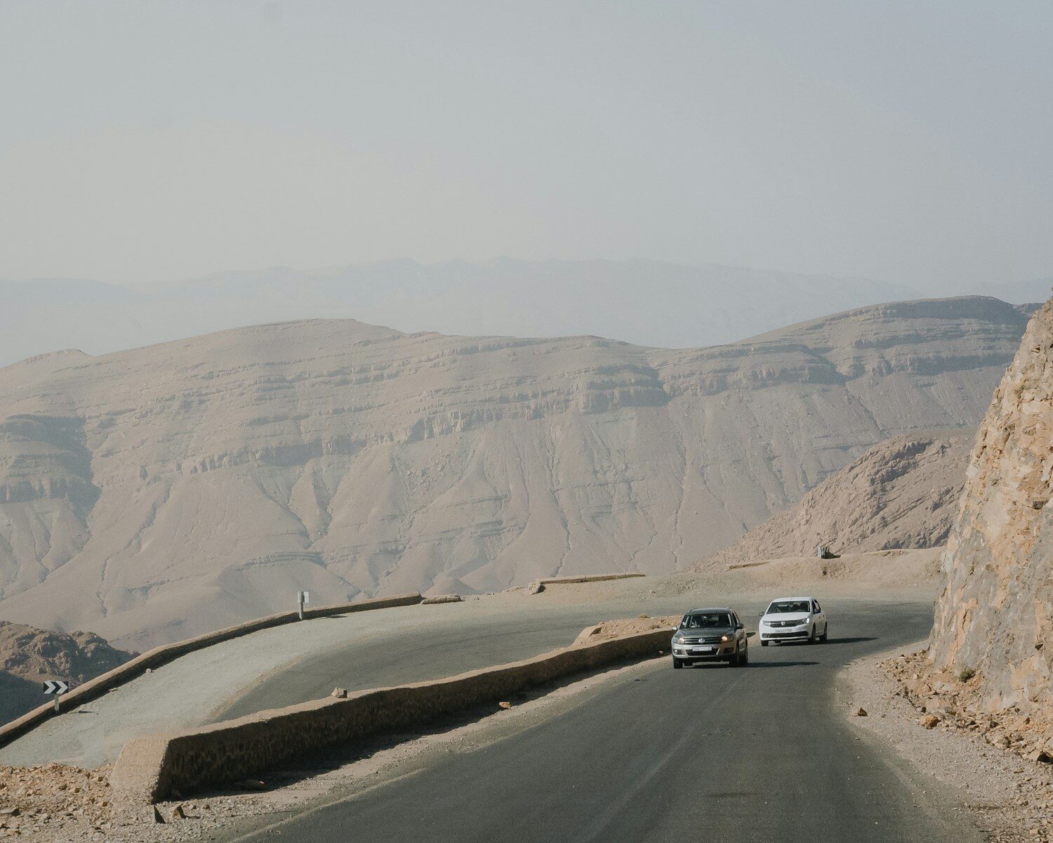 Cars on a winding mountain road toward the Sahara desert in Morocco