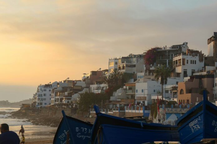 Taghazout village at sunset Taghazout village with white buildings and blue fishing boats at sunset